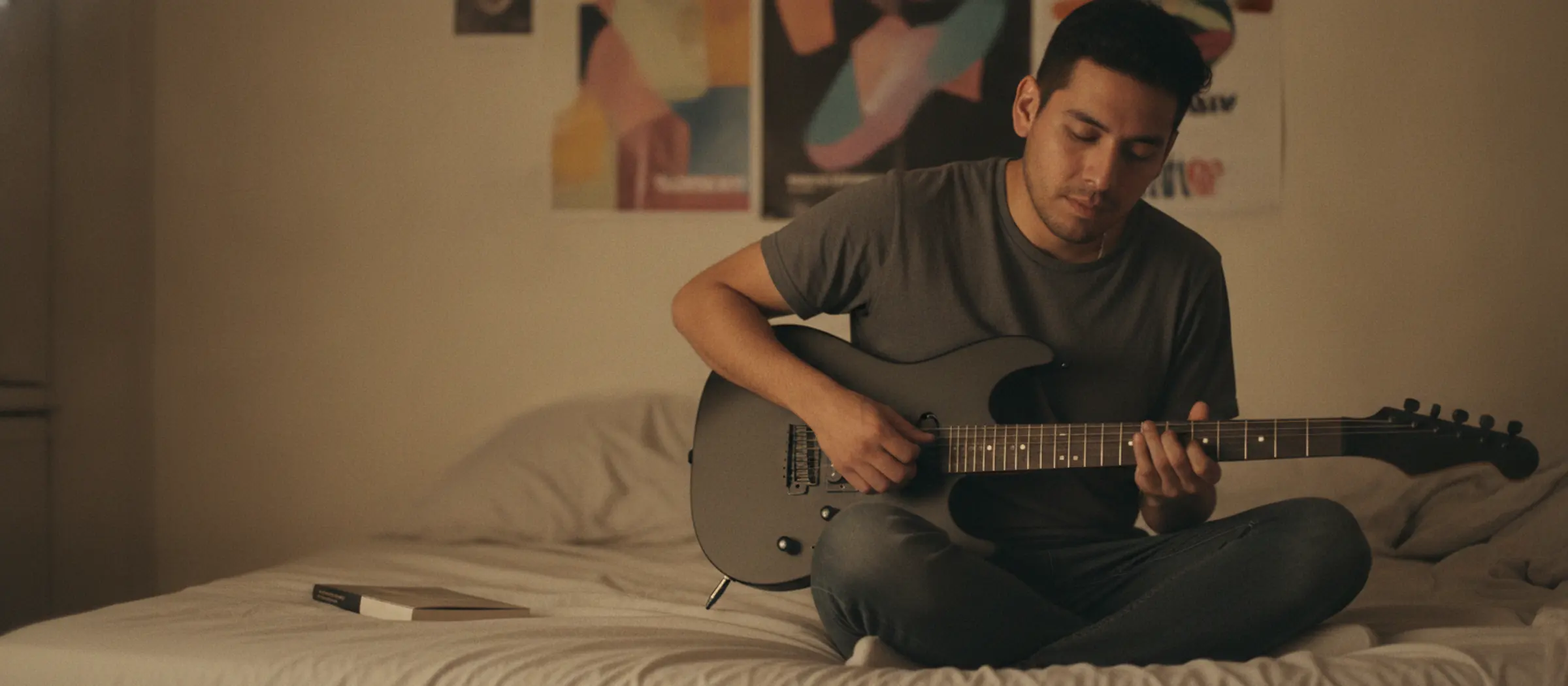 Un chico prueba una guitarra eléctrica usada en su cuarto